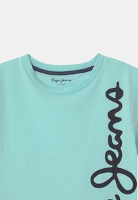 Mintgrøn T-shirt med rund hals; har "Pepe Jeans" logo i sort langs siden; lavet af blødt bomuldsstof.