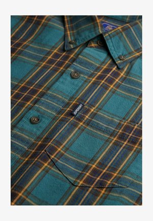 Geruit overhemd in teal en bruin, met knopen, een kraag en een zichtbaar logolabel. Materiaal lijkt zacht met een gestructureerde afwerking.