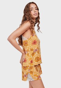Yellow floral tank top with white lace accents and matching shorts, featuring a layered design and intricate flower patterns.