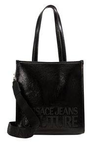 Czarna, błyszcząca torba tote o fakturze z podwójnymi uchwytami oraz regulowanym paskiem na ramię, zdobiona wytłoczonym logo "Versace Jeans Couture".
