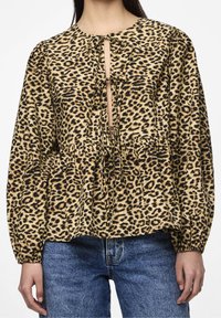 Blusa con stampa leopardata, collo rotondo, maniche lunghe a sbuffo, chiusura con fiocco e vita arricciata. Realizzata in tessuto morbido con una finitura texturizzata.