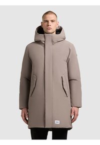 Béžová zateplená parka s vysokým límcem, velkou kapucí a dvěma předními kapsami. Má hladkou texturu a minimalistický design.
