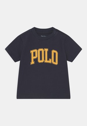 Marineblauw katoenen T-shirt met een geel "POLO" logo in dikke blokletters. Korte mouwen en drukknoopsluiting op de schouder.