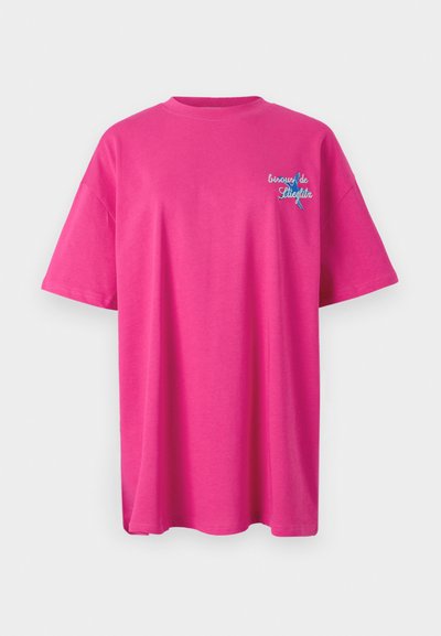 Camiseta de algodón rosa con mangas cortas y cuello redondo. Presenta texto bordado en azul en la parte frontal. Dobladillo recto.