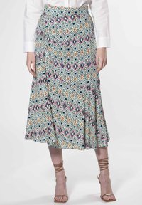 Jupe portefeuille en tissu léger avec un motif géométrique multicolore comprenant des losanges et des cercles, se terminant sous le genou.
