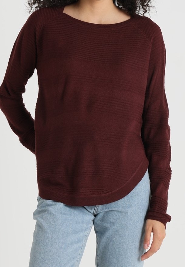 Burgundy, textured sweater with a round neckline and long sleeves; features horizontal stripes and a curved hem; paired with light blue jeans.