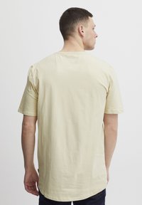 Tricou cu mânecă scurtă, cu gât rotund, din bumbac galben deschis, având o croială lejeră și o textură netedă. Fără modele sau accente vizibile.