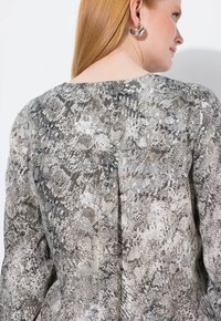 Textureret bluse i slangeprint med nuancer af grå og beige. Har lange ærmer og en diskret rygsøm detalje.
