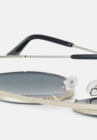 Lunettes de soleil avec des verres dégradés gris, des branches en acétate noir, une monture en métal doré, un logo gravé et des plaquettes de nez transparentes pour le confort.