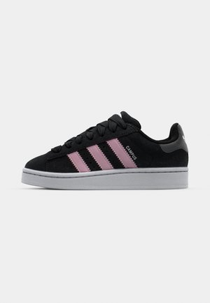 Must musta sneaker, mille roosa kolme triibu kujundus, hall kummi välistald ja tekstureeritud keel. Sisaldab brändingut külgedel ja kanna peal.