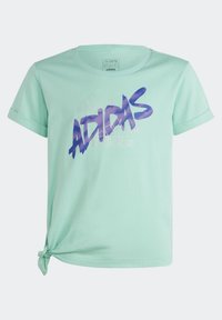 Tyrkysové tričko vyrobené z bavlny, s uzlovým detailem na boku a výrazným fialovým grafikou "adidas" na přední straně.