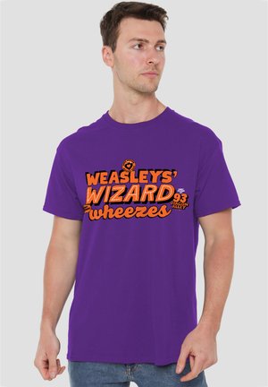 Man wearing a purple T-shirt with orange text reading "Weasleys' Wizard Wheezes" and small wizard-themed graphics on the chest.