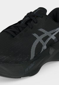 Μαύρο αθλητικό παπούτσι ASICS με γκρι λωρίδες λογότυπου, αναπνεύσιμο επάνω μέρος από δίχτυ, κορδόνια και πάτο με πάχος και επένδυση με την ετικέτα FF Turbo².
