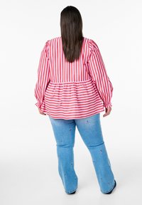 Sarkanais un baltais svītrainais krekls ar puffed piedurknēm; pepluma jostas vieta. Apvienots ar ziliem izplestiem džinsiem, kuros ir neliela ziedu izšūšana.