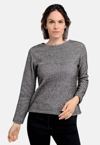 Grau melierter Pullover im Fischgrätmuster mit Rundhalsausschnitt und langen Ärmeln, kombiniert mit dunklen Jeans, die eine glatte Textur und eine taillierte Passform aufweisen.
