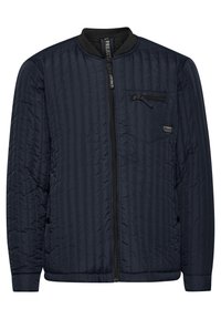 Giacca bomber trapuntata blu navy con colletto a costine, chiusura con zip e tasca sul petto con zip a contrasto. Design leggero e texture raffinata.