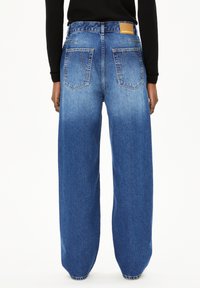 Wijdvallende jeans in vervaagd blauw denim met een gestructureerde afwerking. Voorzien van een bruine label op de achterste tailleband en twee achterzakken.