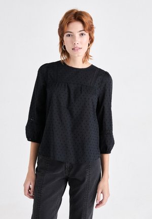 Black blouse with 3/4 puff sleeves, textured fabric featuring small, raised dots, and subtle lace detailing along the sleeves and neckline.