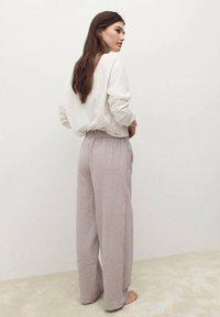 Maglietta lunga beige chiaro con una vestibilità comoda, abbinata a pantaloni larghi a righe rosa e bianche con una vita elasticizzata.