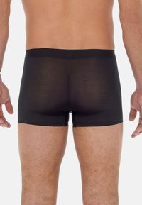 Black boxer shorts featuring a soft waistband and smooth, lightweight fabric. The design offers a fitted cut with a seamless back.