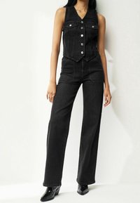 Schwarzer Jeans-Overall mit einem ärmellosen Oberteil und Druckknopfverschluss, hoch taillierten, weit geschnittenen Hosen und Fronttaschen.