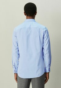 Hele sinine pikkade varrukatega särk, millel on tekstuuriga muster, ühe nupuga varrukaotsad ja lai kaelus. Disainitud kõveriku servaga.