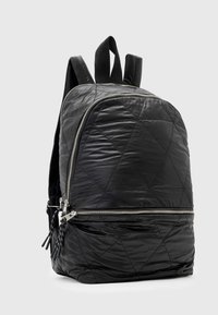 Zaino in nylon nero trapuntato con forma arrotondata, dotato di cerniere argentate, due spallacci e una tasca frontale con chiusura a cerniera.