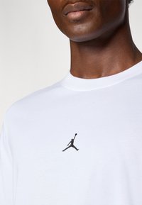 Hvid bomulds t-shirt med et lille sort Jumpman-logo på venstre brystområde. Rund halsudskæring med en glat tekstur.