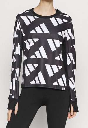 Black long-sleeve athletic top with abstract white geometric patterns worn with black leggings, finger holes in sleeves visible.