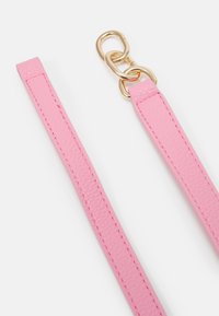 Deux brides en cuir rose texturé reliées par trois maillons de chaîne en métal doré sur fond blanc.
