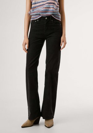 Jeans a zampa nera in corduroy con cinque tasche, chiusura frontale con bottone e una sottile texture, abbinati a un top in maglia multicolore a righe.