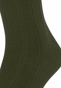 Calza verde scuro a coste che mette in mostra la texture e la forma, evidenziando la vestibilità confortevole e i dettagli di design.