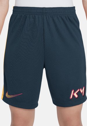 Pantaloncini sportivi blu navy con vita elastica, banda laterale gialla, logo Nike Swoosh rosa e giallo sulla gamba sinistra e logo "K M" sulla gamba destra.