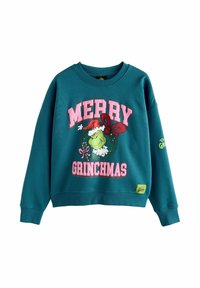 Teal színű pulóver, amelyen egy nyomtatott minta látható, rajta a "MERRY GRINCHMAS" felirattal rózsaszínben, egy Grincs grafikával, valamint egy zöld logós folttal az alján.