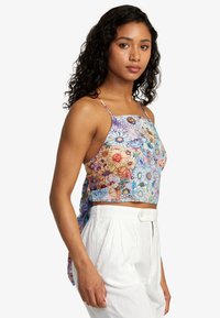 Floral crop top with thin straps, featuring a multicolored abstract flower pattern on a light background. Smooth fabric, fitted design.