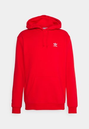 Czerwona bluza z kapturem Adidas z przednią kieszenią na brzuchu, regulowanym sznurkiem przy kapturze, ściągaczami na rękawach i małym białym logo Adidas na lewej piersi.
