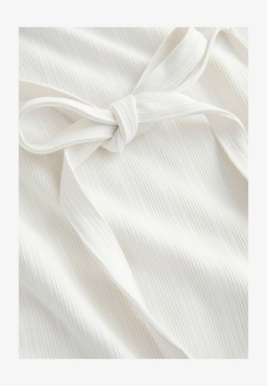 Weißer Stoff mit vertikaler Rippenstruktur und einem gebundenen Schleifendetail. Glatte Oberfläche mit weichem Fall und dezentem Glanz.