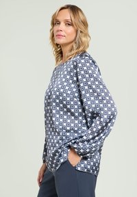 Langærmet bluse i blågrå med geometrisk mønster, med en afslappet pasform og rund halsudskæring. Blødt stof med en glat tekstur.
