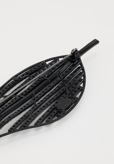 Vassoio nero a forma di foglia realizzato in plastica texturizzata, con motivi perforati e bordo intrecciato, completo di un piccolo cartellino attaccato.