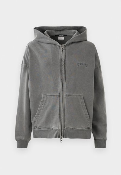 Grå zip-up hoodie med en rymlig huva, framfickor och broderad logotypdetalj. Tillverkad av mjukt, texturerat tyg med ribbade ärmmuddar.