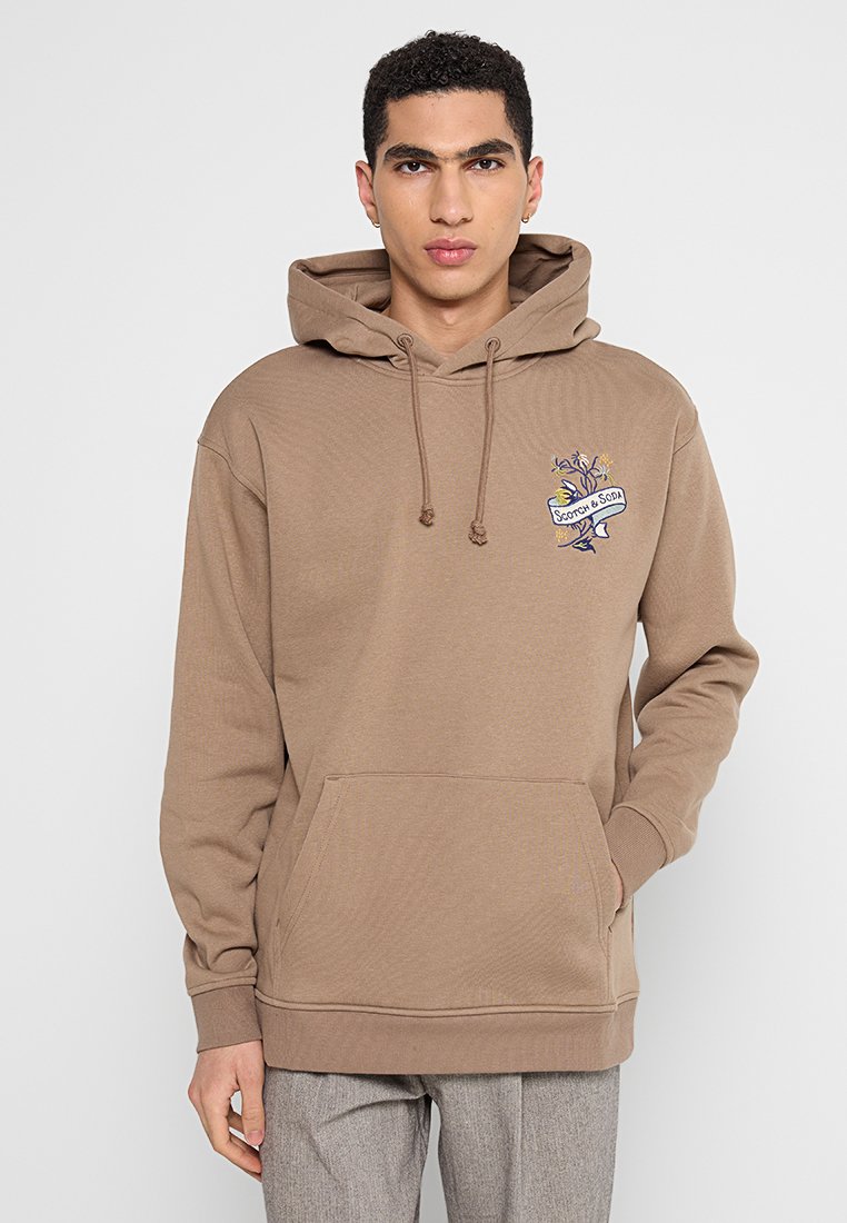 Bruine hoodie gemaakt van zachte stof, met een voorzak en een geborduurd ontwerp op de borst, inclusief verstelbare koorden.