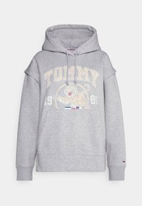 Harmaa huppari, joka on valmistettu puuvillasekoitteesta ja jossa on kengurutasku. Siinä on sana "TOMMY" sekä tiikerikuvio beigeinä ja valkoisina. Säädettävä huppu nyörillä.