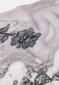 Suave tela gris con un patrón de encaje floral negro y pliegues sutiles que crean textura y profundidad.