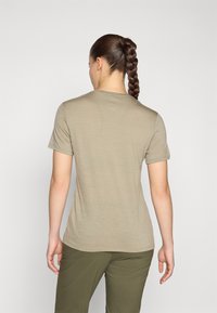 Camisa de manga corta verde oliva hecha de una tela ligera, con un cuello redondo y una textura suave. Llevada con pantalones verdes a juego.