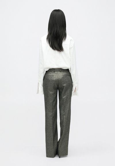 Bijela košulja dugih rukava s dugmadi na manžetama, u kombinaciji s krojenim sivo uzorcima hlačama, stvarajući siluetu ravnih nogavica.