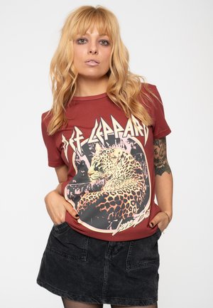 Maroon graphic t-shirt featuring a leopard design and "Def Leppard" text. Short sleeves and relaxed fit, paired with a black skirt.