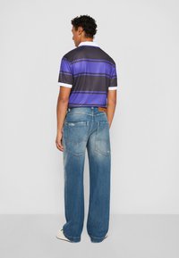 Purple and black striped polo shirt with white collar, paired with wide-leg faded blue jeans featuring back pockets and minimal distressing.