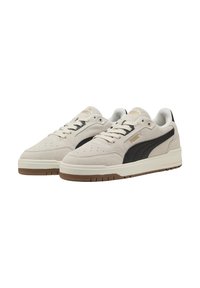 Baskets en suède beige avec bande noire PUMA, semelle blanche et semelle en caoutchouc brun. Présentent des détails perforés et des lacets plats.