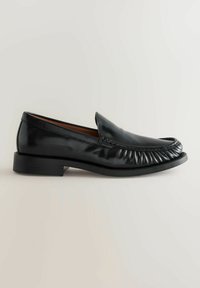 Mocasines de cuero negro con punta redondeada, detalles gather en la parte superior y un tacón bajo apilado para mayor estabilidad. Acabado suave y brillante.