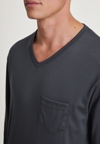 T-shirt a maniche lunghe grigio scuro con scollatura a V, realizzato in tessuto morbido, con una tasca sul lato sinistro del petto con dettagli cuciti.